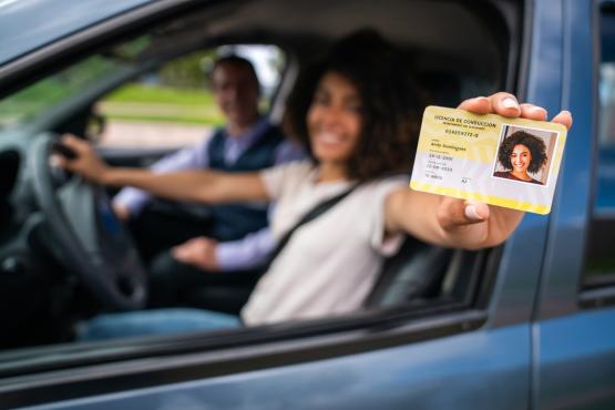 Woman holding a licence in a car