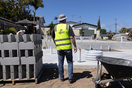 Worker wearing a QBCC high-visibility vest on a construction site