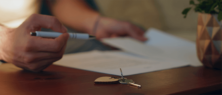 desk hands pen signing contract house keys